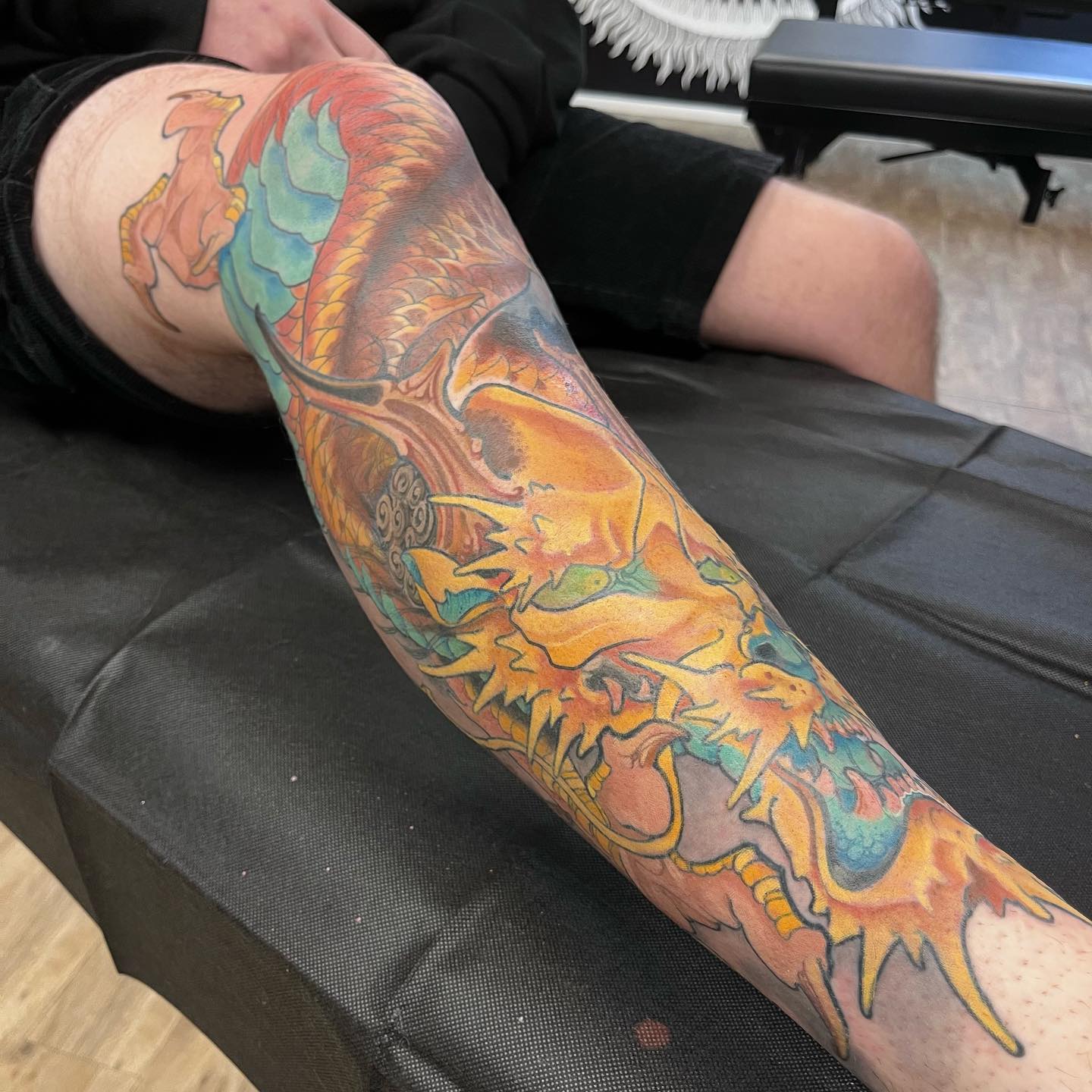 Full leg dragon sleeve tattoo orange and teal